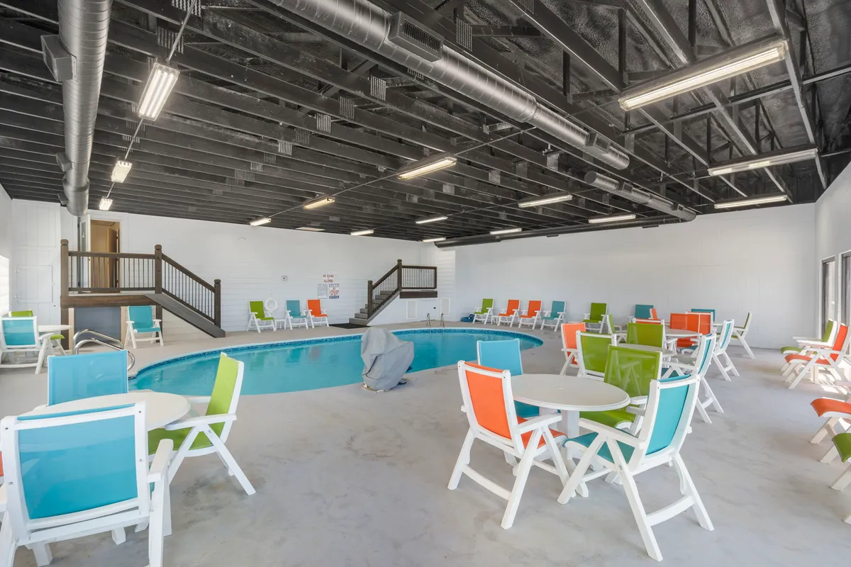 A bright, modern indoor swimming pool with colorful chairs and tables around the pool deck. The setting is refreshing and lively, yet intimate enough for couples to unwind after a day of adventure or exploration.